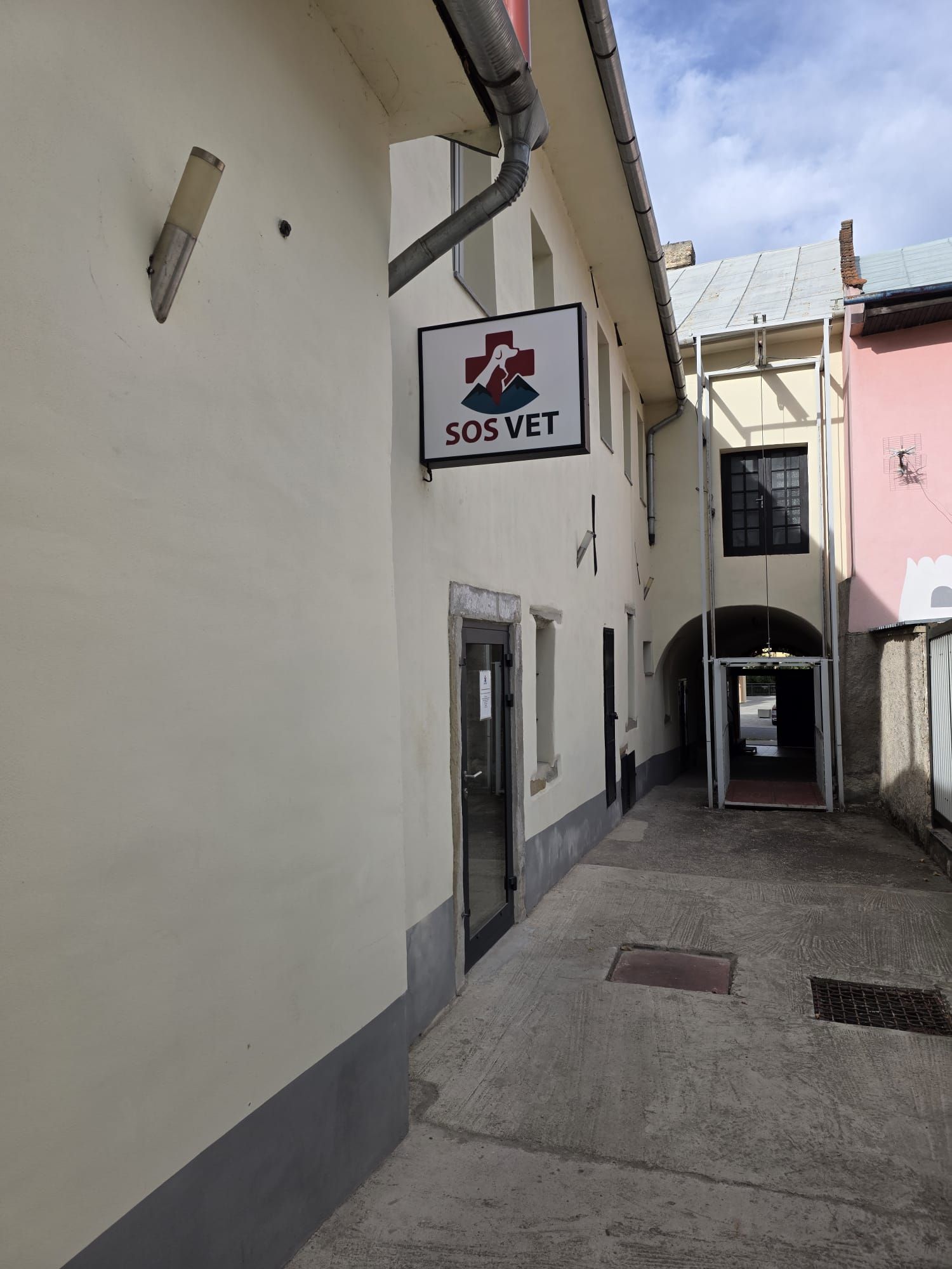 Stará brána z ulice do dvora, nad dverami tabuľa SOS Vet